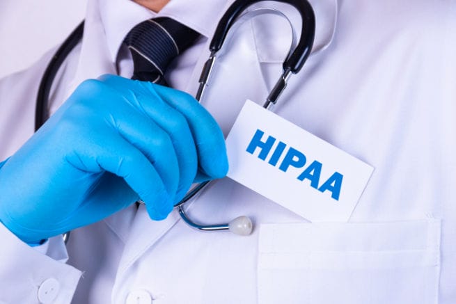 Doctor holding HIPAA compliance card to highlight healthcare data security