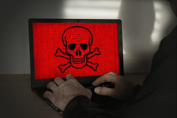Ransomware attack warning on laptop screen with red skull and crossbones