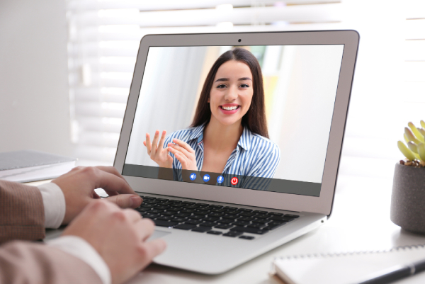 Person smiling during a video call on a laptop—representing secure HIPAA-compliant telehealth via Google Meet.